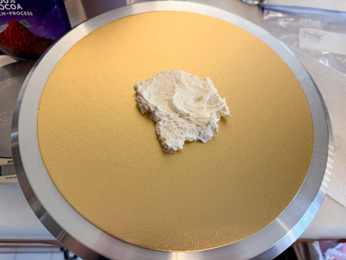 a round gold cake board with vanilla buttercream in the center