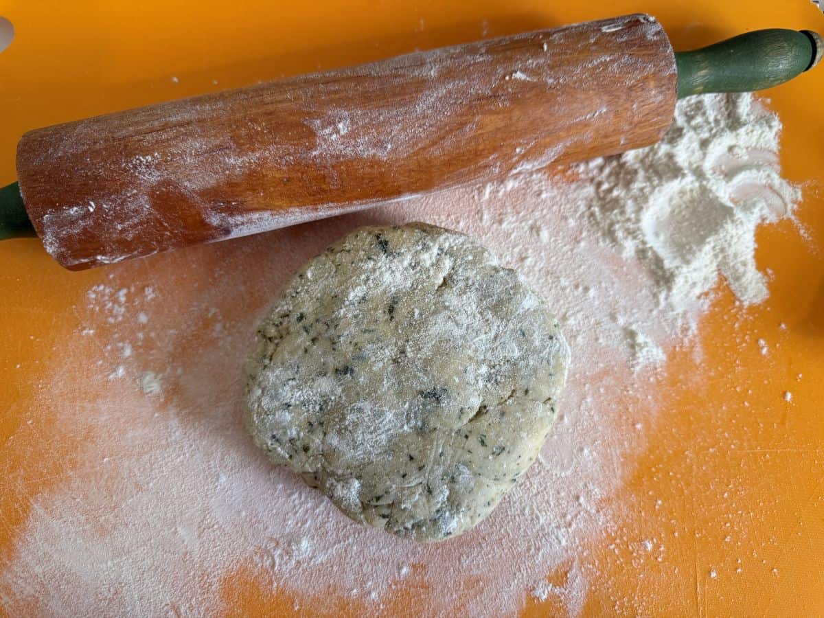 a disc of tart dough on a floured cutting mat next to a rolling pin