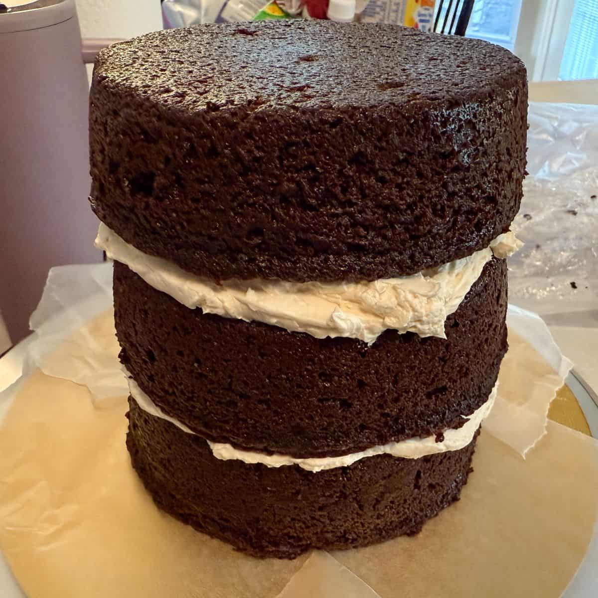 three layers of 6-inch chocolate cakes with vanilla buttercream in between stacked on a gold cake board