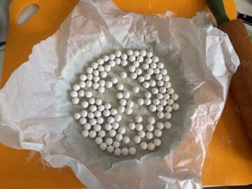 a tart shell covered with a piece of parchment paper and pie weights