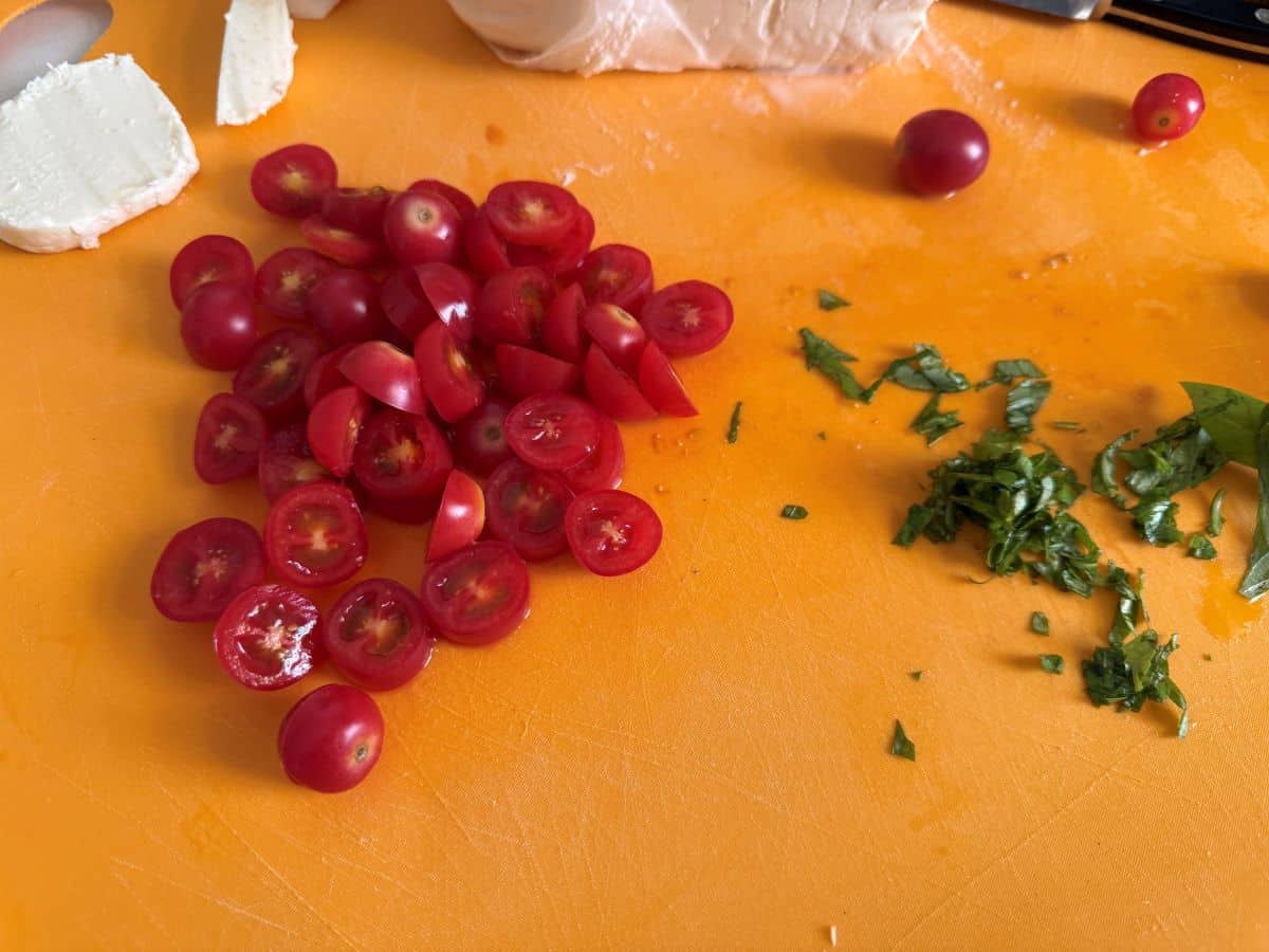 tomatoes chopped on a cutting board next so some fresh chopped basil