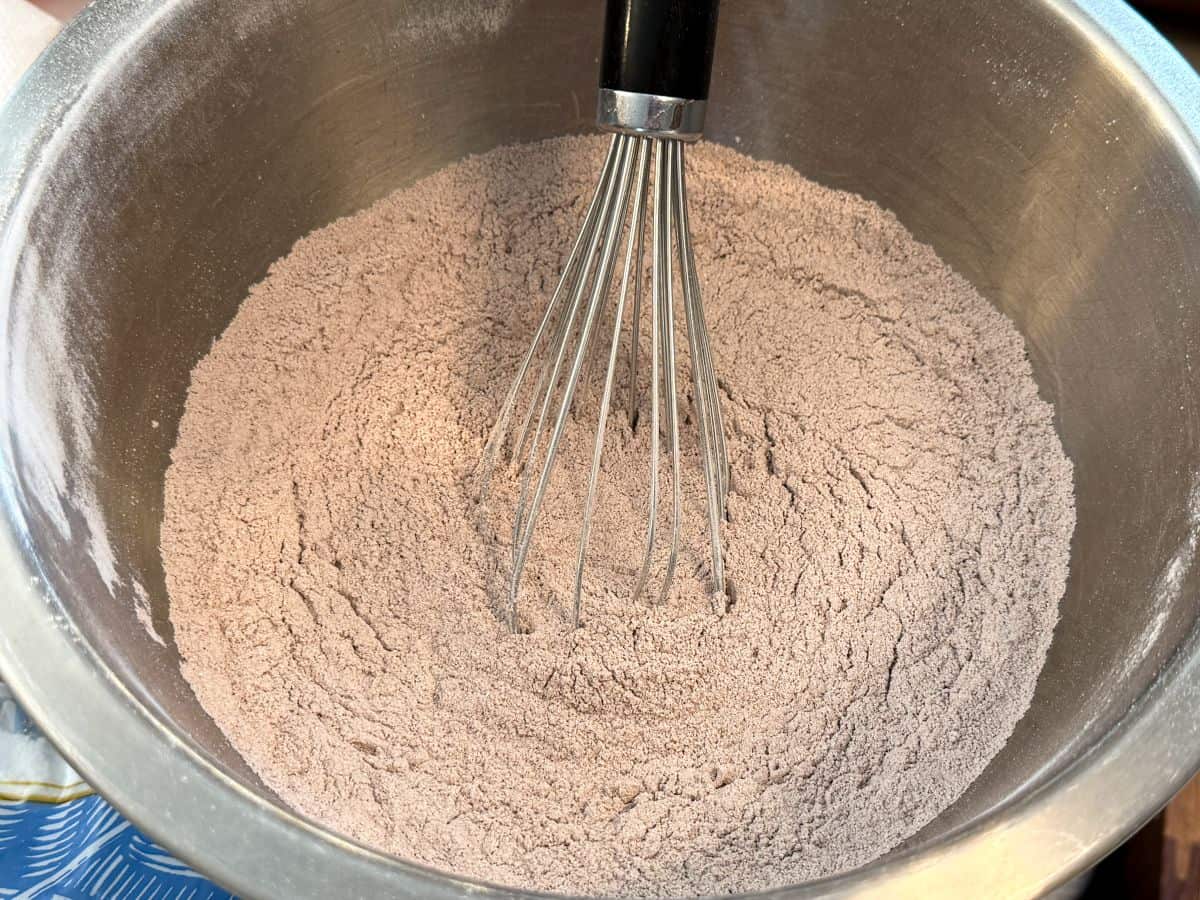 dry ingredients for chocolate nut free macarons in a bowl with a wire whisk