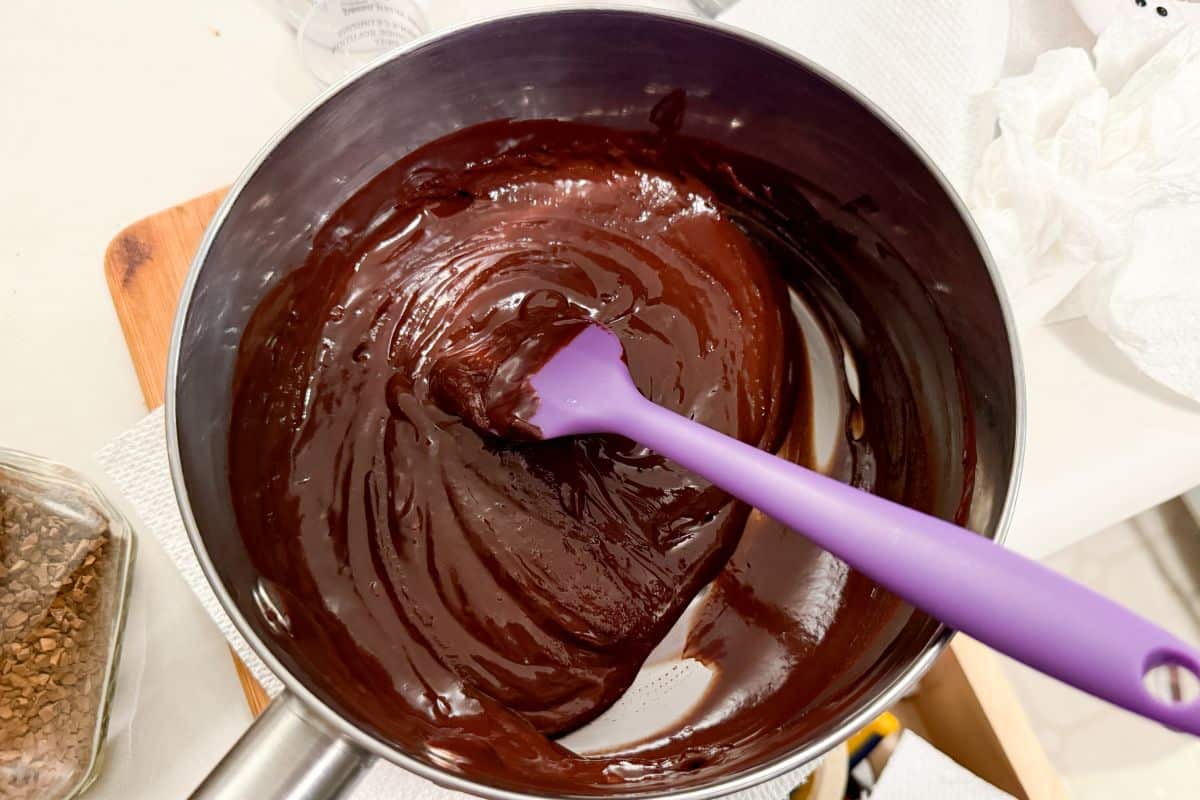 chocolate ganache in the top of a double boiler with a small silicone spatula in it