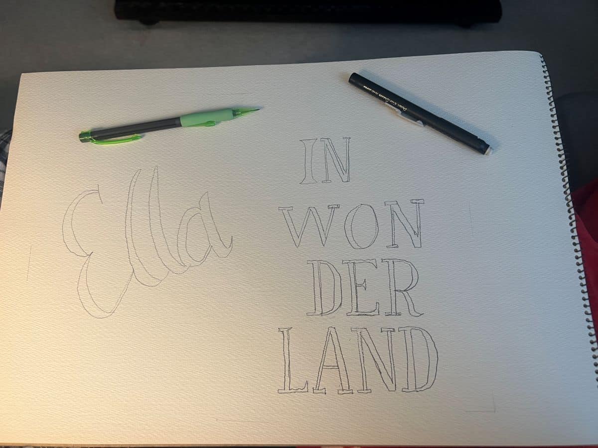 a pencil outline lettering on a sign for "Ella in Wonderland"