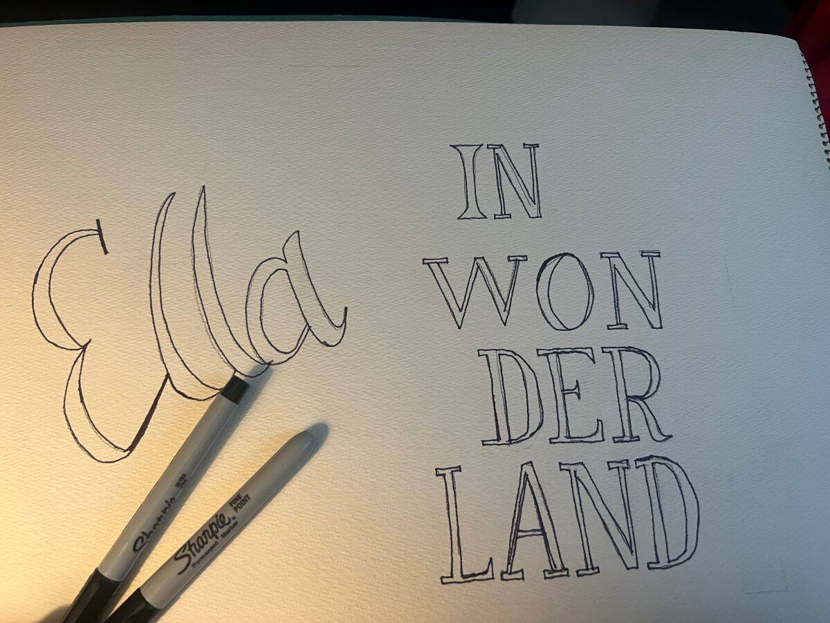 thin and medium black Sharpies on top of an "Ella in Wonderland" sign