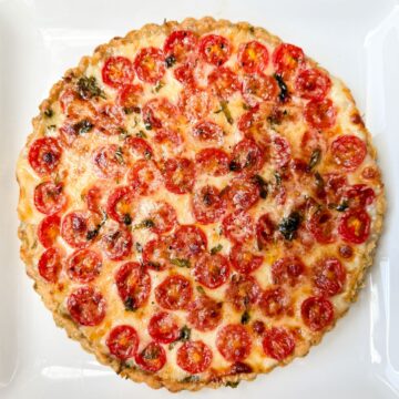 a tomato mozzarella tart with garlic basil crust on a white plate
