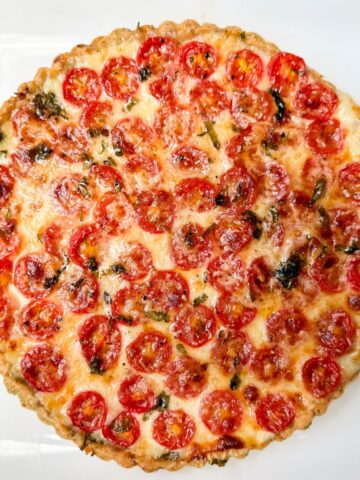 a tomato mozzarella tart with garlic basil crust on a white plate