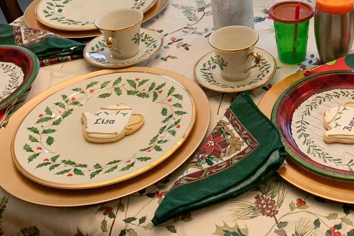 a holiday table set with Christmas china and personalized holly teapot cookies at each plate
