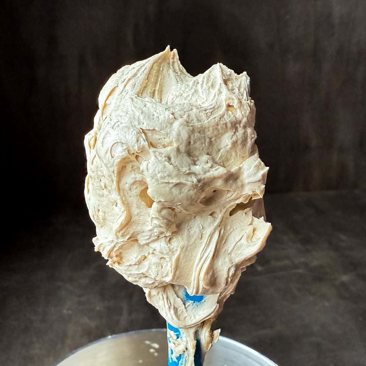 Easy Coffee Buttercream on a spatula held up over a bowl
