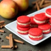 Nut Free Apple Macchiato Macarons on a white platter with apples and cinnamon sticks around it