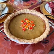 Painted Pie Crust Leaves in the center of a pumpkin pie on a Thanksgiving table