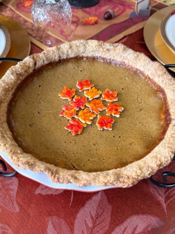 Painted Pie Crust Leaves in the center of a pumpkin pie on a Thanksgiving table