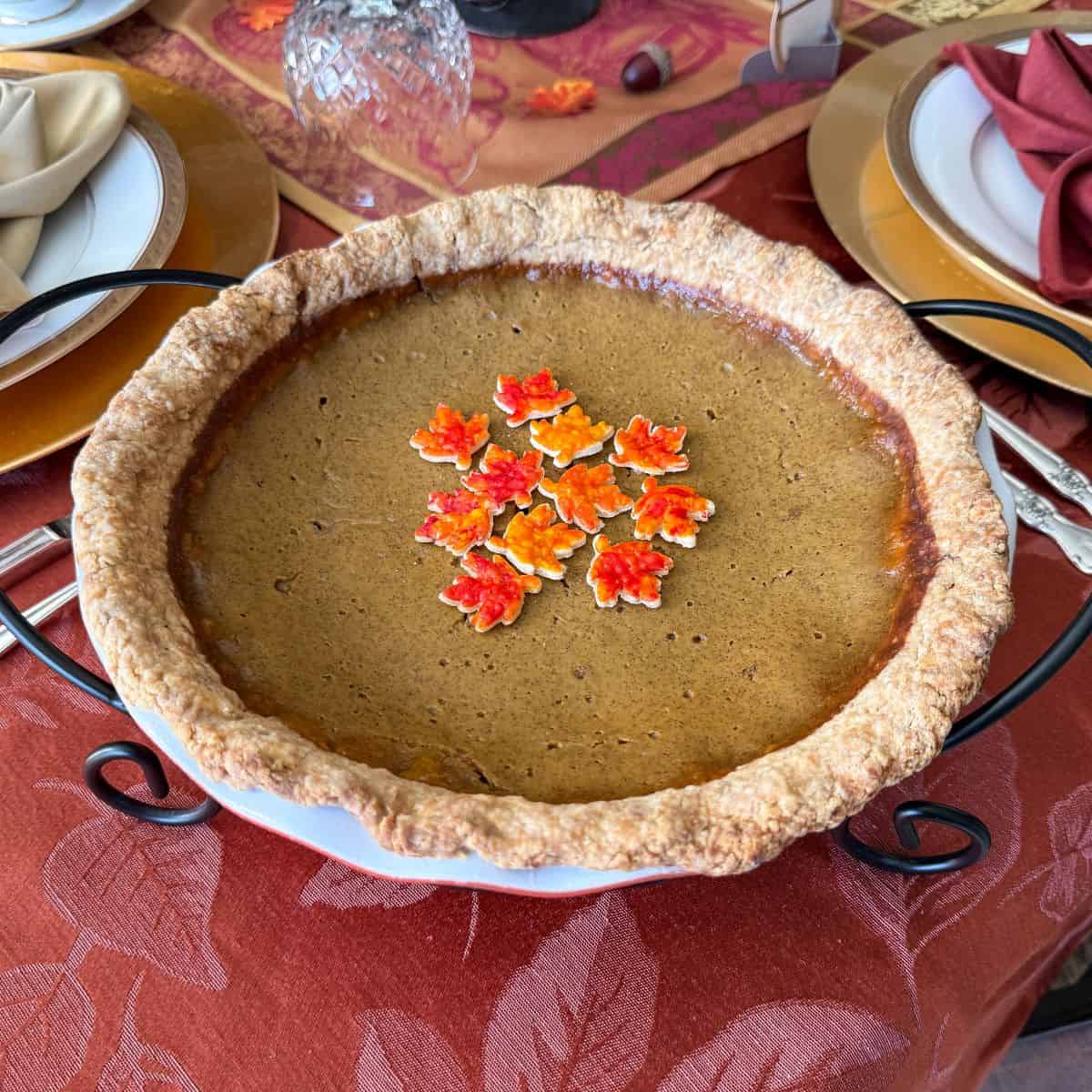 Painted Pie Crust Leaves in the center of a pumpkin pie on a Thanksgiving table