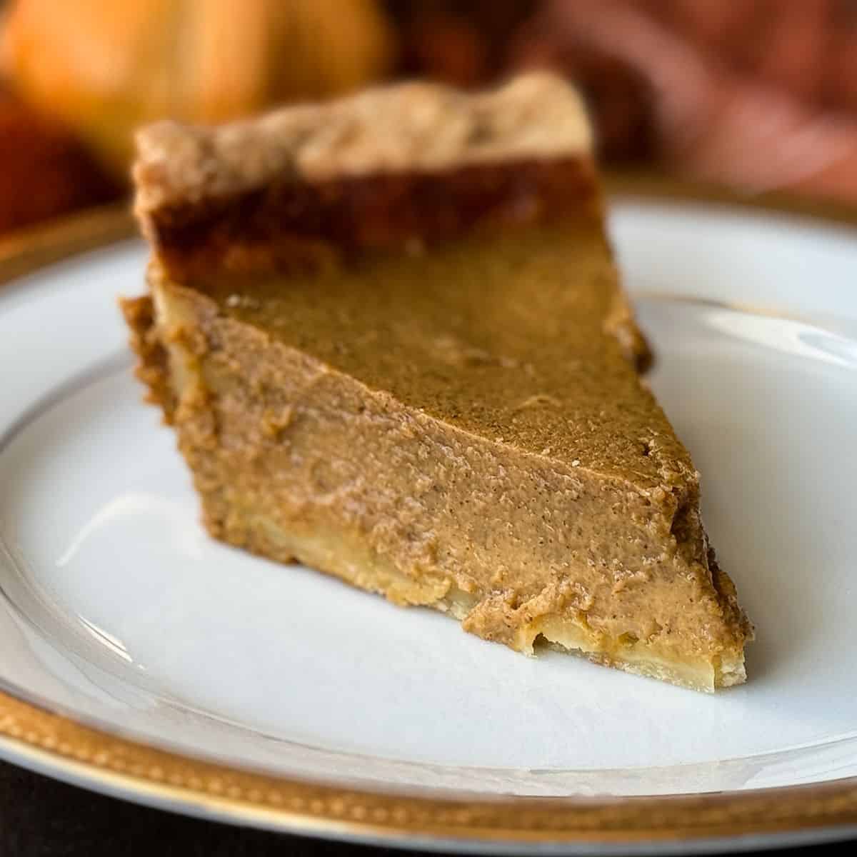 a slice of Rich Pumpkin Pie on a white china plate