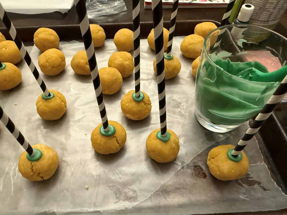 black and white paper straws stuck into cake pops with melted green candy melts