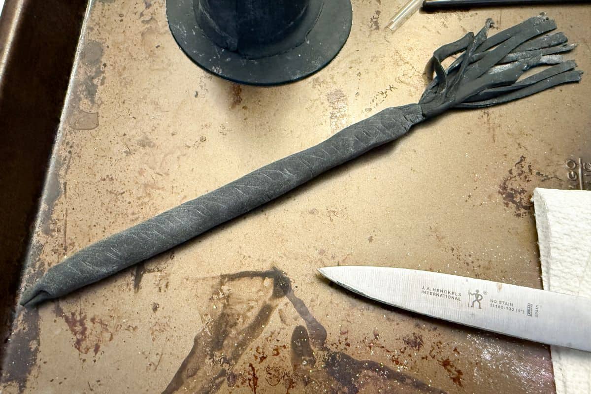a black fondant witches broom next to the black fondant hat