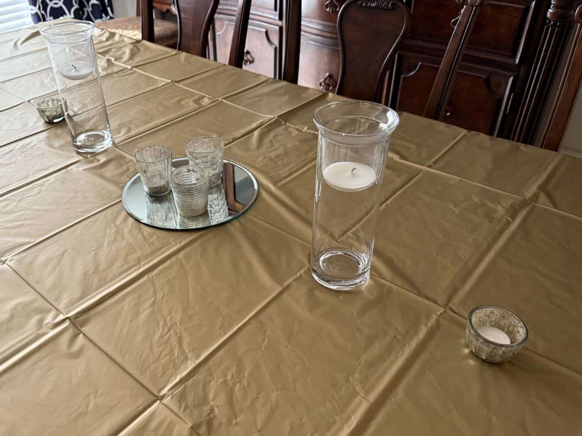 a gold tablecloth covered table with silver decor down the center