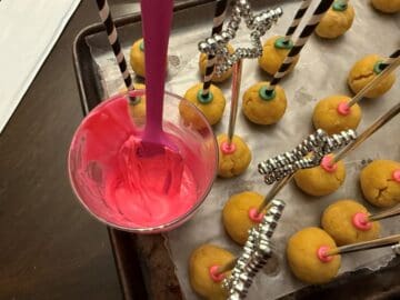 melted pink candy melts in a glass next to cake pops