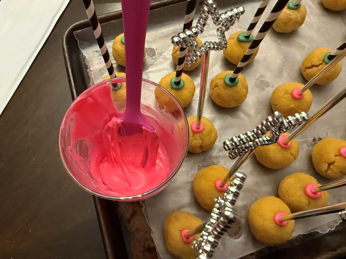 melted pink candy melts in a glass next to cake pops
