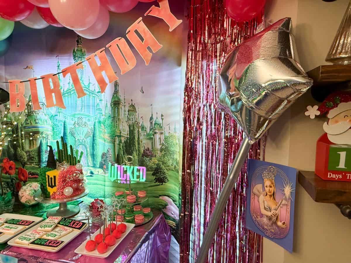 Glinda poster and balloon wand next to a WICKED dessert table