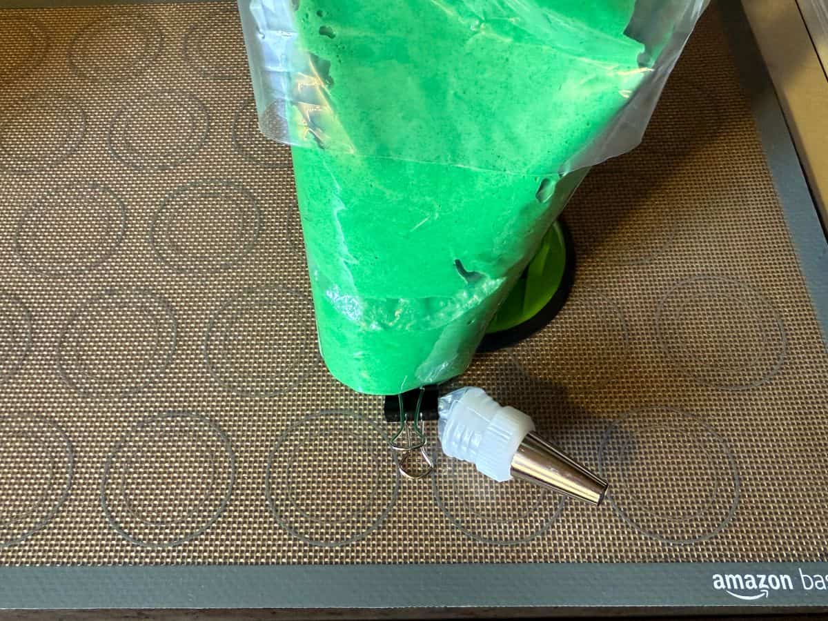 green macaron batter in a disposable piping bag fitted with a medium round tip
