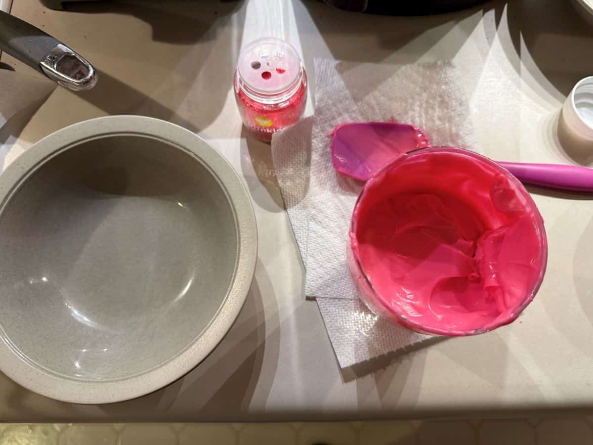 melted pink candy melts in a glass next to a bowl and a container of sanding sugar