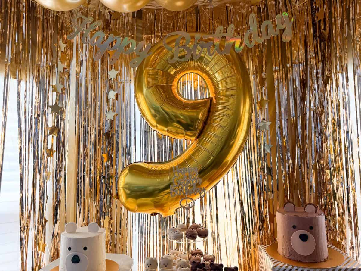 a big gold 9 balloon hanging over a teddy bear dessert table