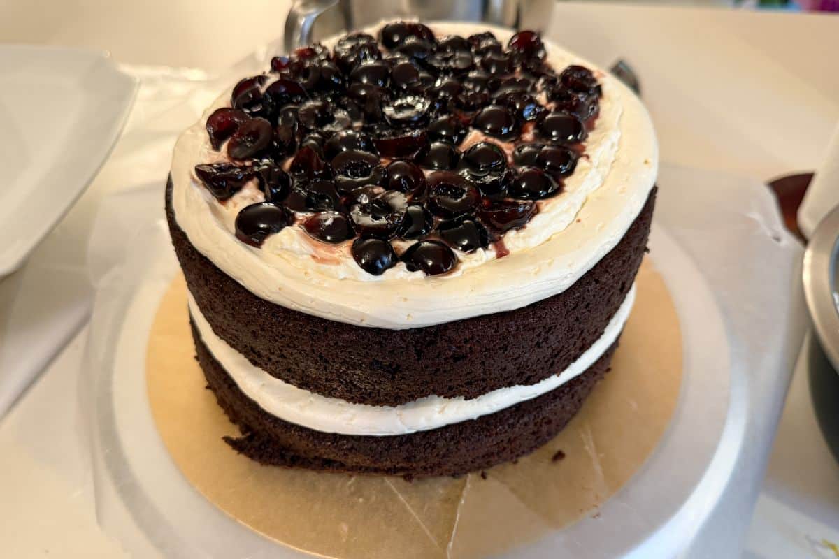 chopped amarena cherries on top of whipped cream on 2 layers of chocolate cake