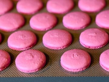 pink macaron shells baked on a macaron mat