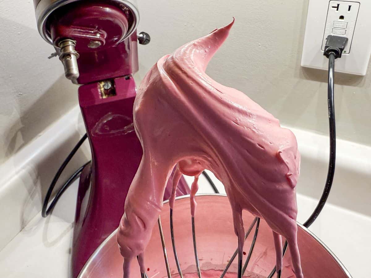 pink meringue in a stiff peak on a wire whisk attachment