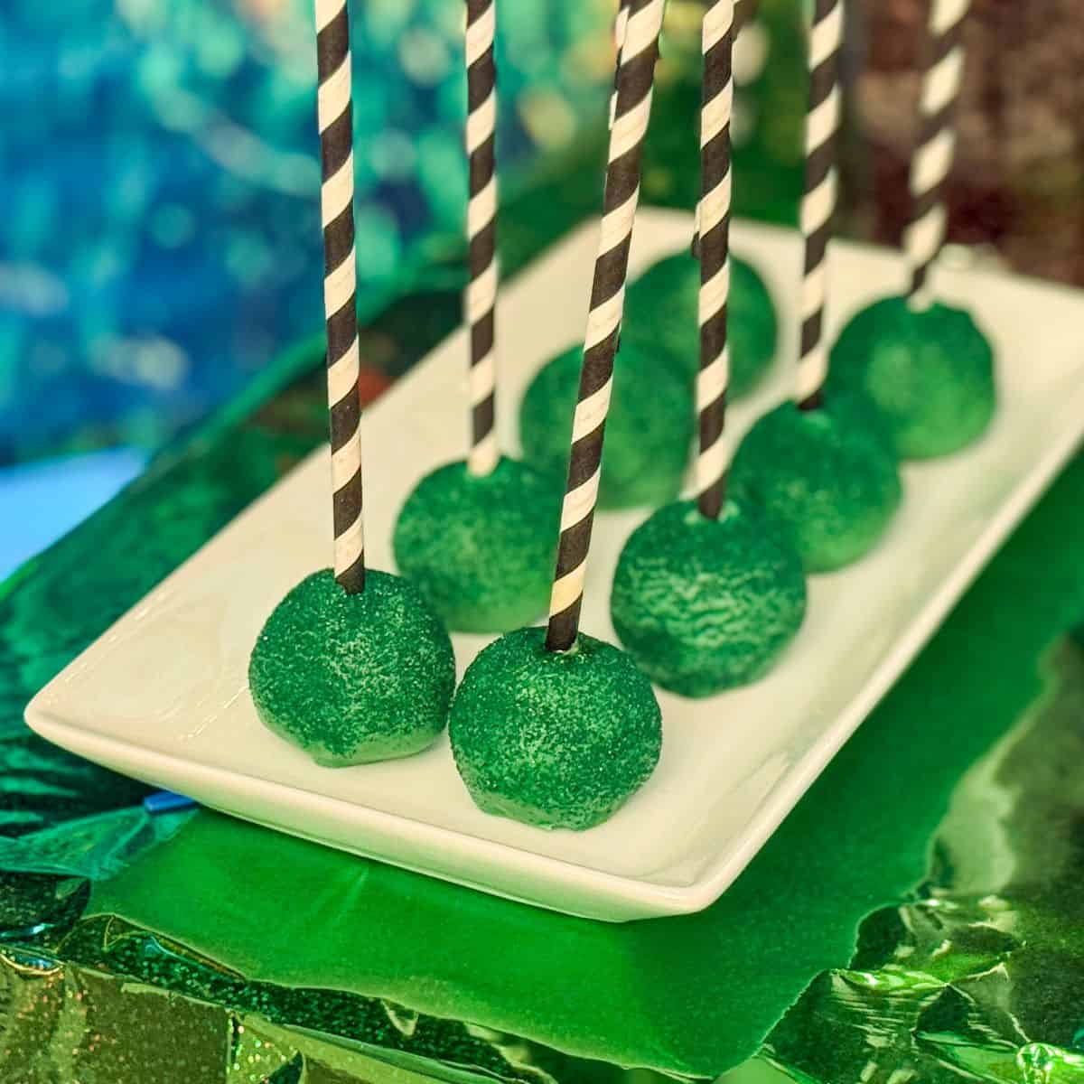 Wicked Cake Pops that are green with black and white straw sticks