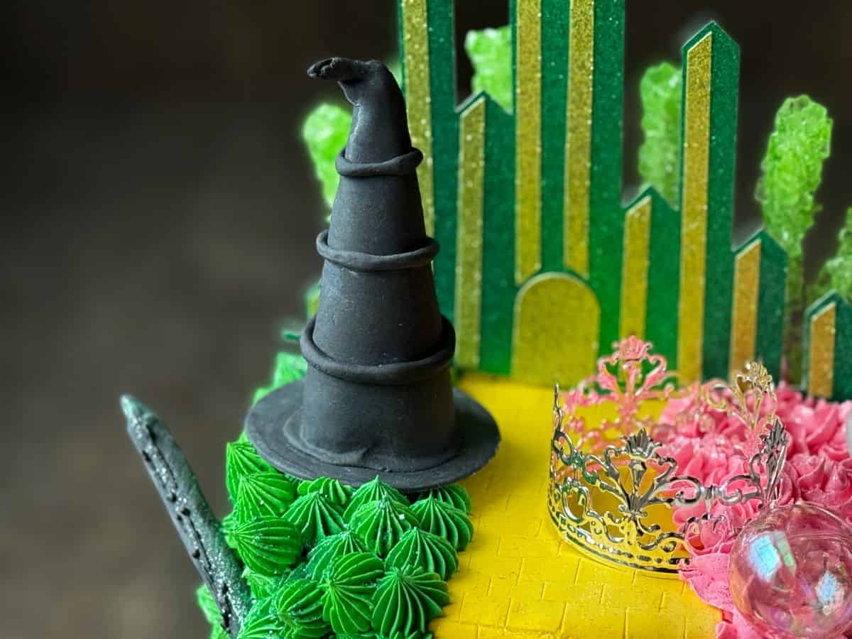 a black fondant witches hat on the top of a Wicked Birthday Cake