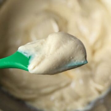 Eggnog Pastry Cream on a green silicone spatula held over a bowl with the cream