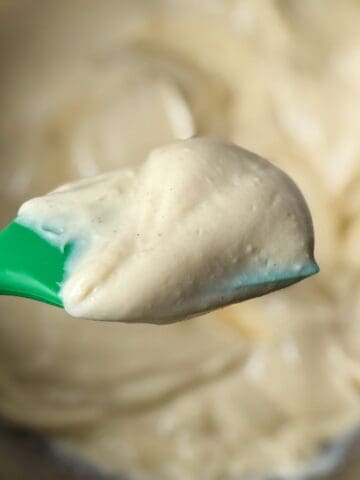 Eggnog Pastry Cream on a green silicone spatula held over a bowl with the cream