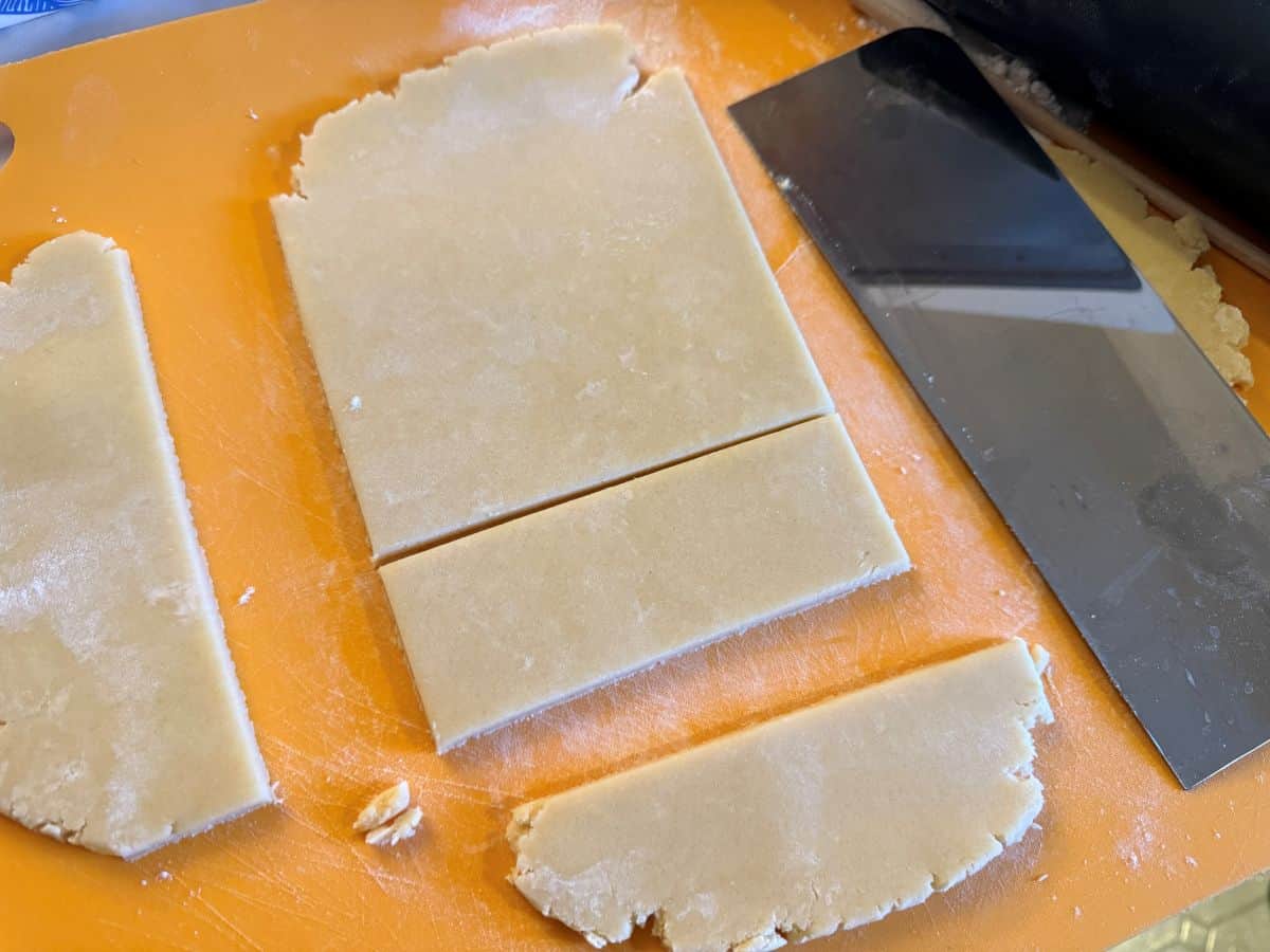 sugar cookie dough rolled on a mat and cut into a rectangle