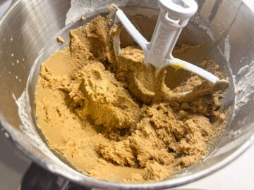cookie dough in a stand mixer bowl with a beater in the bowl