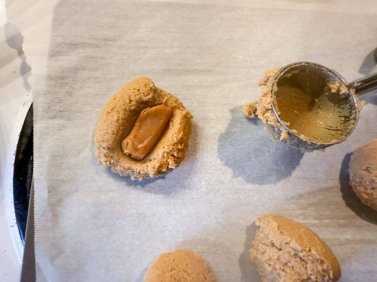 an unwrapped soft caramel on top of a ball of browned butter dough