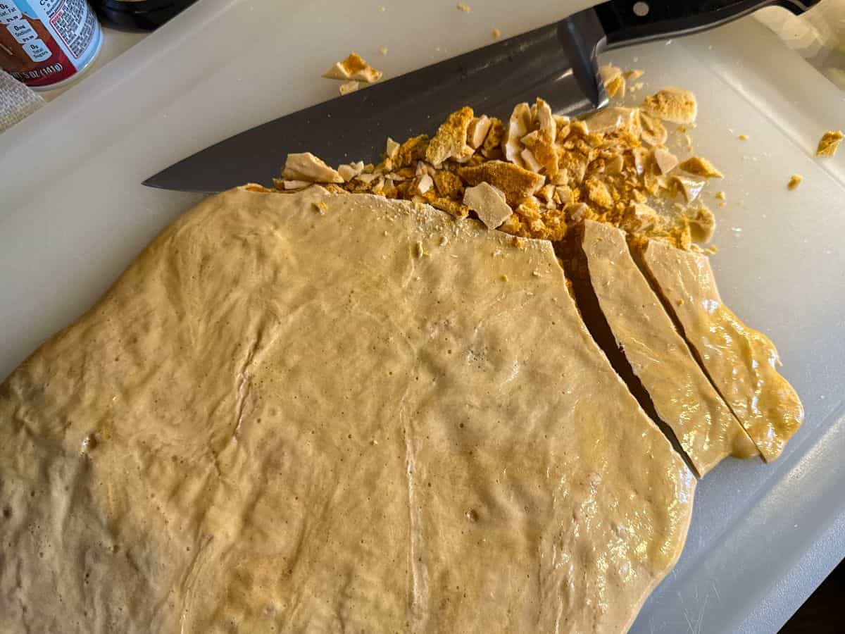 coffee crunch candy on a cutting board with a knife starting to chop it into pieces