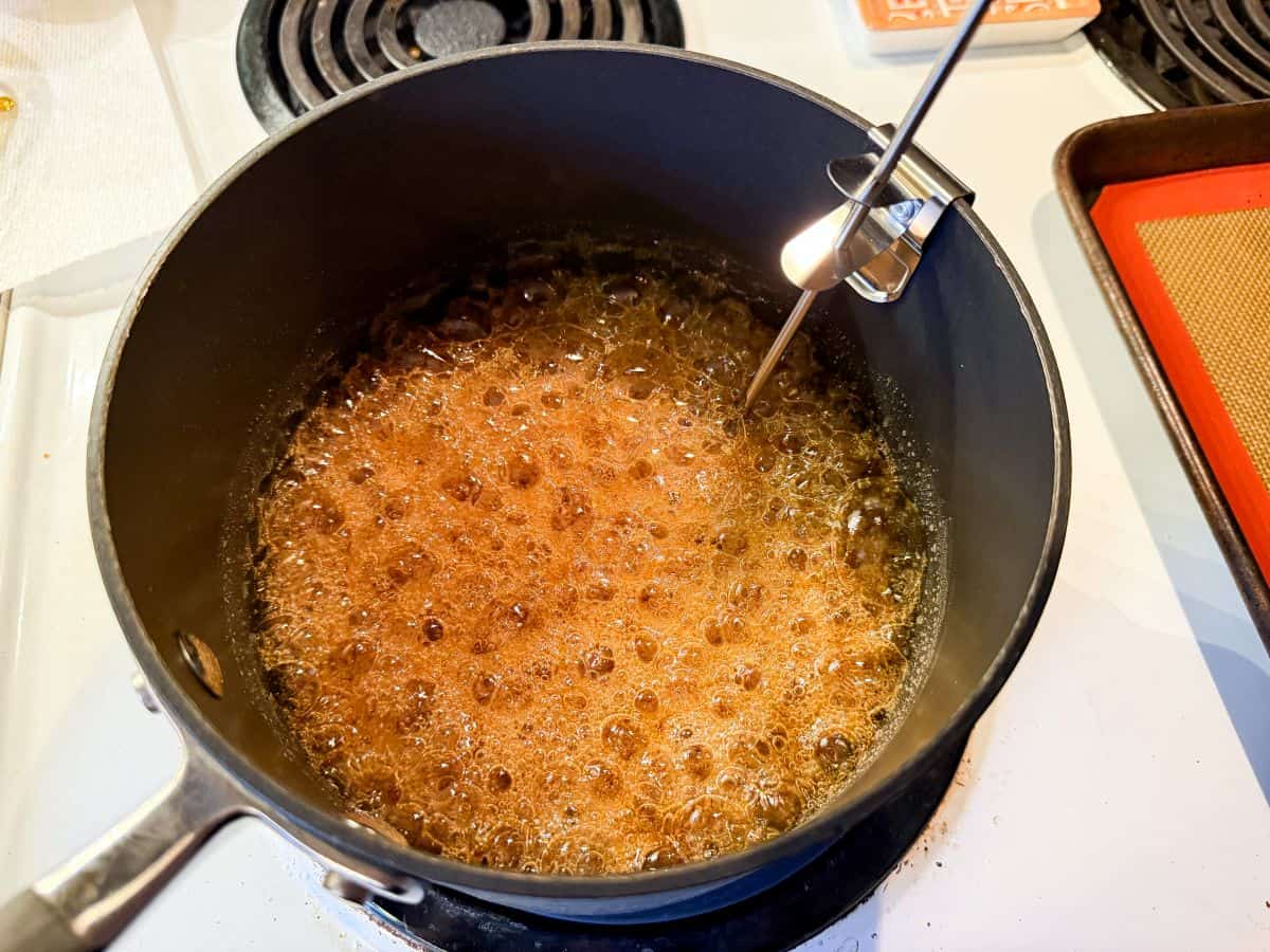 coffee crunch candy bubbling in a saucepan with a candy thermometer in the pan