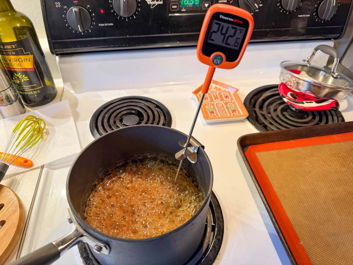 candy cooking in a pot on the stove with a digital candy thermometer in it