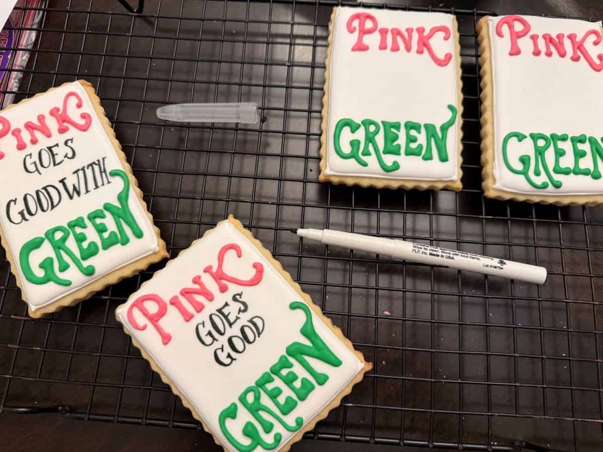 white royal icing cookies with black edible marker to write on cookies "Pink goes good with green"