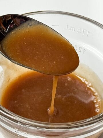 Easy Homemade Butterscotch Sauce dripping off a spoon into a glass bowl