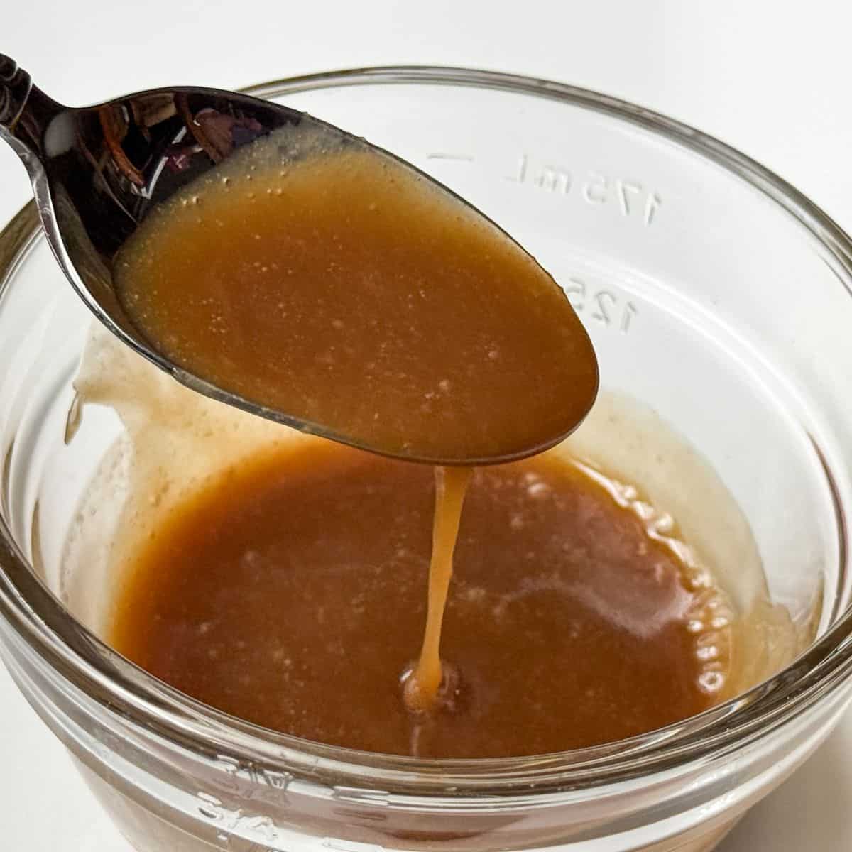 Easy Homemade Butterscotch Sauce dripping off a spoon into a glass bowl