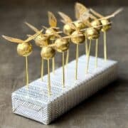 Golden Snitch Brigadeiros on gold sticks in a cake pop display block