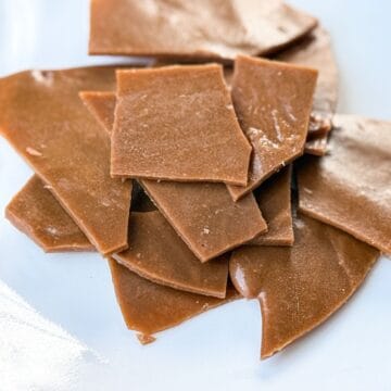 Nut Free Toffee broken into pieces and stacked on a white plate