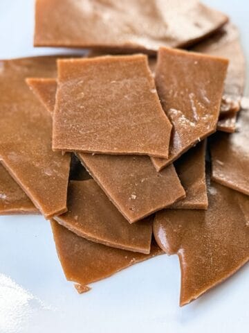 Nut Free Toffee broken into pieces and stacked on a white plate