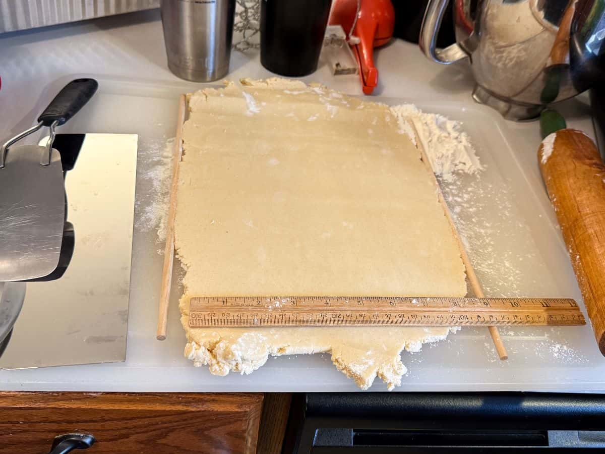 cookie dough rolled out to an even thickness on a counter with a ruler on top