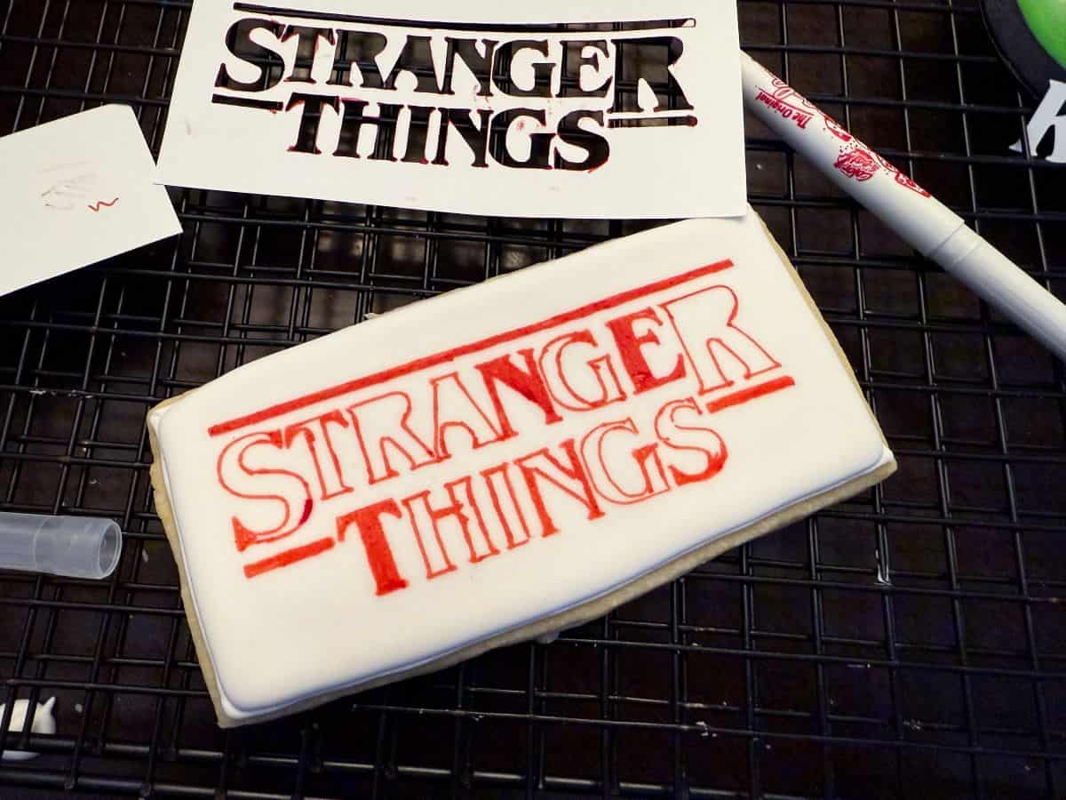 red edible marker drawn on a white royal icing cookie with the Stranger Things logo