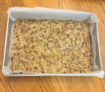 Date Bar batter spread evenly in a parchment paper lined rectangular cake pan