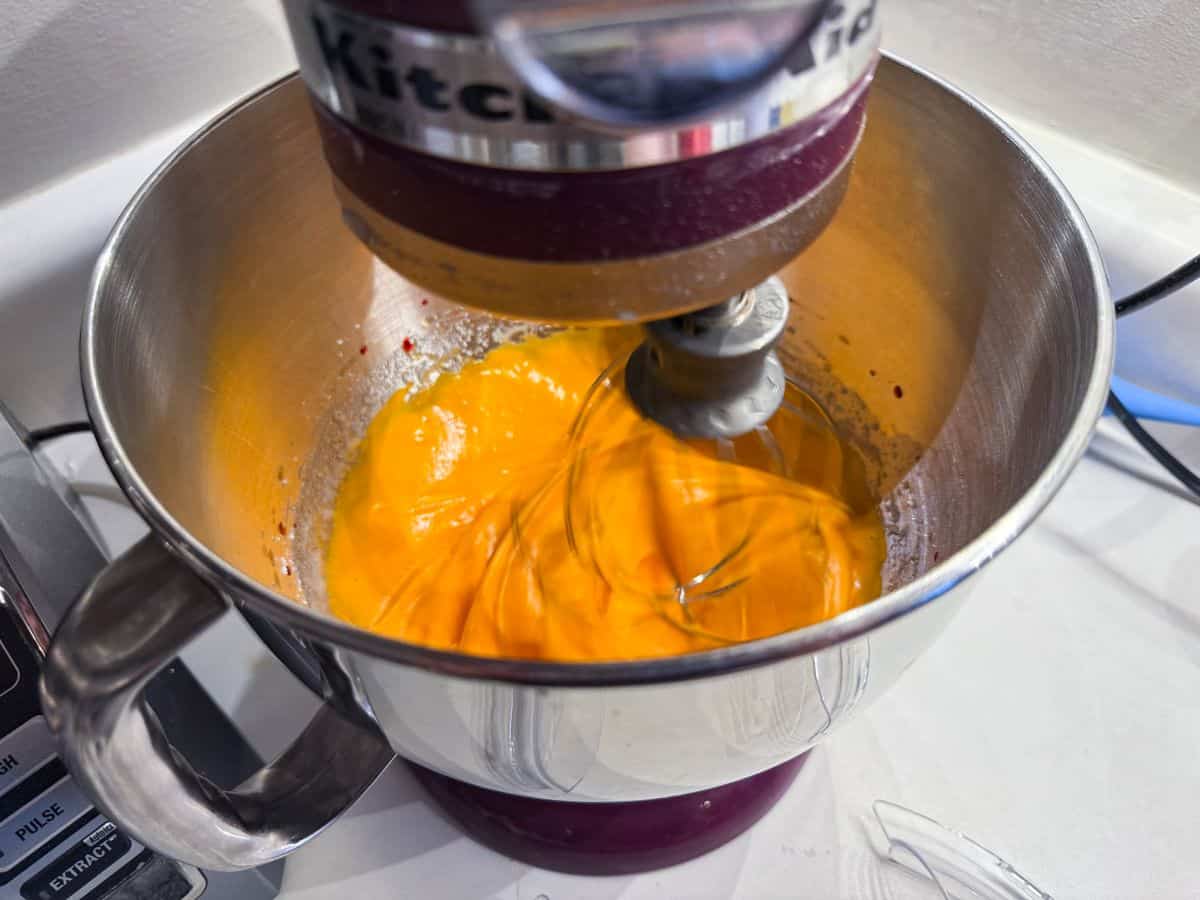 orange meringue mixing in the bowl of a stand mixer